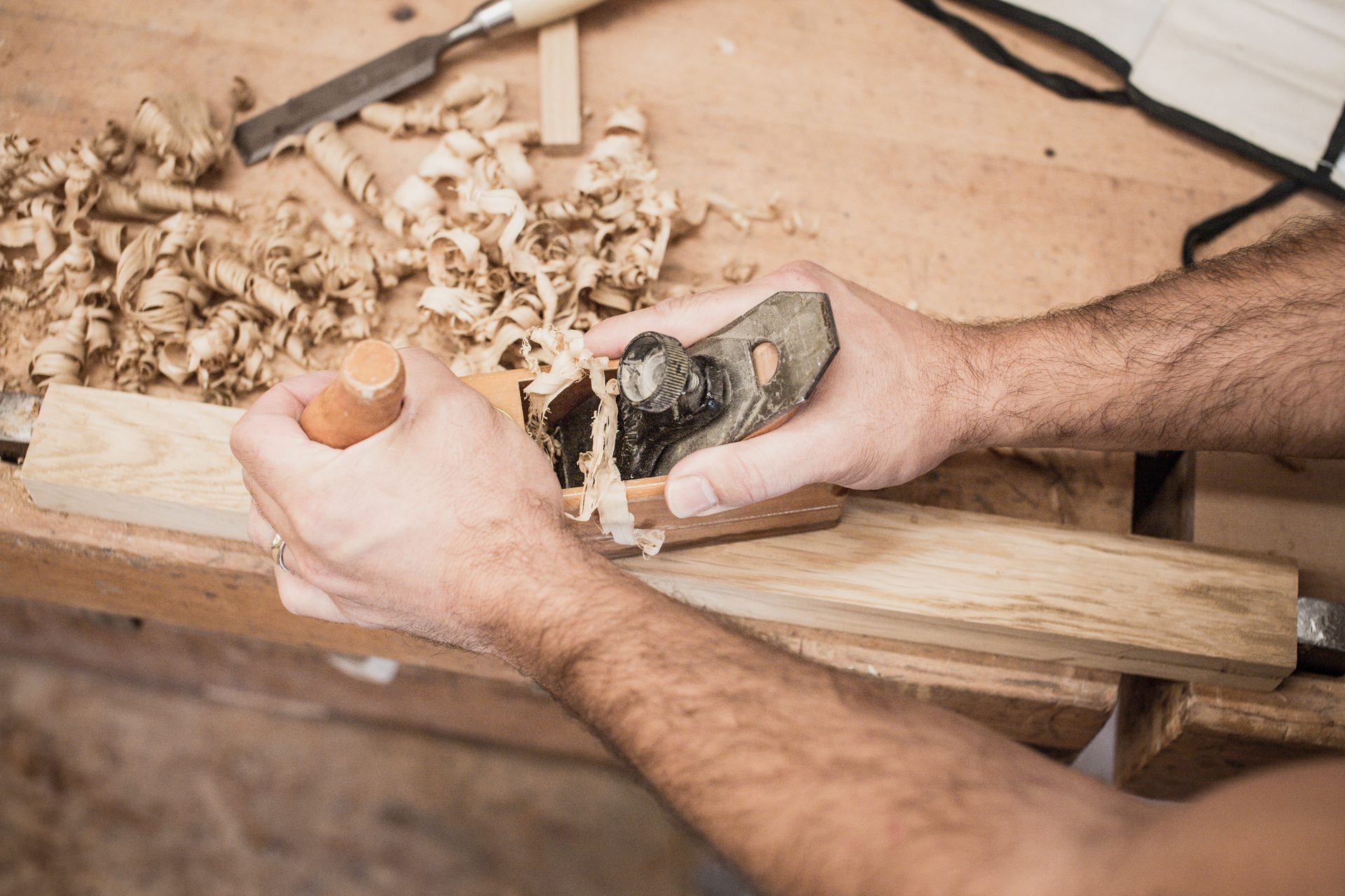 Hände beim Hobeln von Massivholz — Handwerkskunst Schreinerei Holzdesign Grünwald